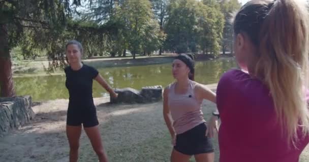 Group Three Women Engage Stretching Routine Outdoors Picturesque Lake Emphasizing — Stock Video