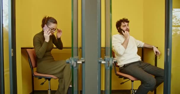 两个人在一个黄色的办公室里 在电话上 展示着现代的工作生活和交流 — 图库视频影像