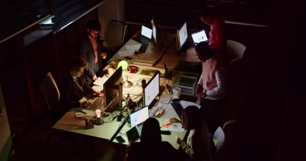 一组专注的商业专业人员在黑暗的办公室里用电脑屏幕照明 在正常工作时间之外高效地协作 — 图库视频影像
