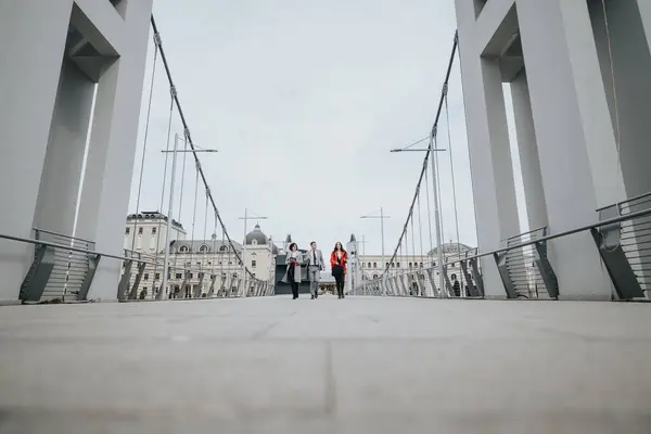 A group of professional lawyers engage in an outdoor meeting, crossing a modern bridge in an urban environment, signifying progress and consultation.