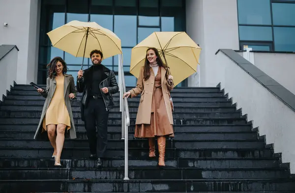 Veselá Trojice Žlutými Deštníky Sestupuje Schodech Ukazuje Přátelství Radost Během — Stock fotografie