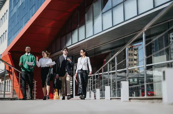 A group of professional businesspeople engage in a meeting while walking in a city on a bright day.