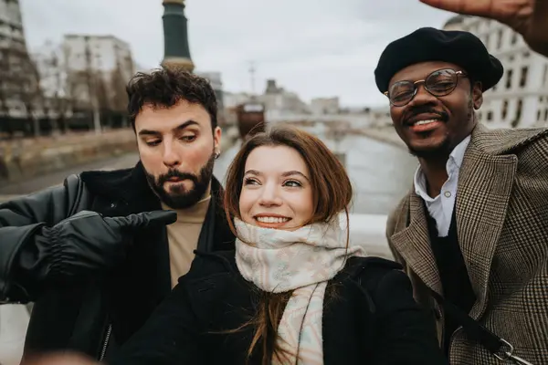 A multicultural trio of young business professionals enjoys a light moment, capturing a selfie together in a dynamic city backdrop.