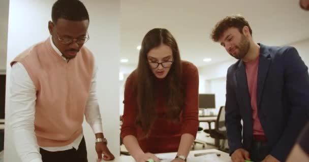 다민족 그룹은 빛나는 현대적인 공간에서 테이블 주위의 계획에 협력하여 팀워크의 — 비디오