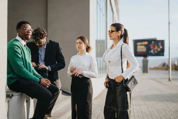 A dynamic group of young startup professionals engaged in a business discussion outside, surrounded by city architecture during a remote project meeting.
