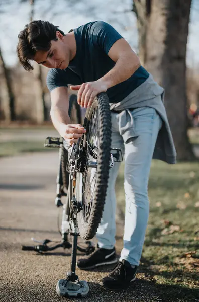 日当たりの良い日に自転車を修理するスタンドを使用して男性を集中させ 自立と屋外活動を披露します — ストック写真