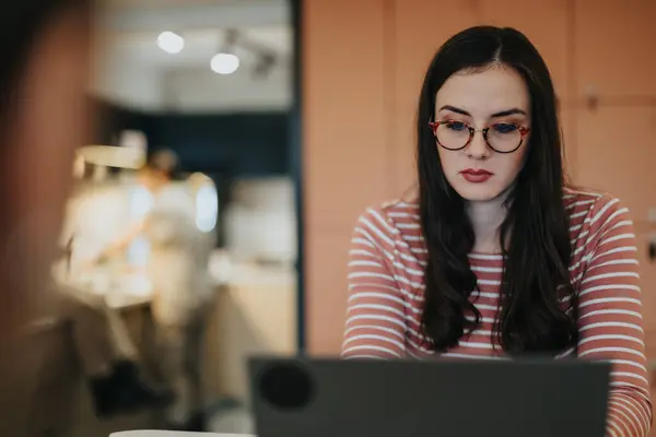 Modern Kafede Dizüstü Bilgisayarda Çalışan Gözlüklü Konsantre Genç Bir Kadın — Stok fotoğraf