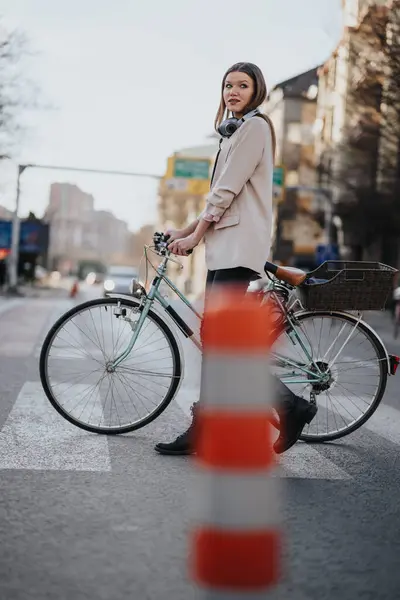 Confident Female Cyclist Headphones Pausing Urban Crosswalk Showcasing Sustainable Transportation — Stock Photo, Image