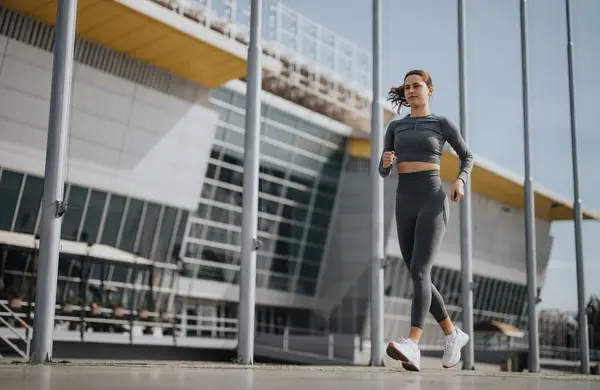 在现代城市环境中 积极参加体育运动的年轻女子穿着慢跑 表现出健康的生活方式和决心 — 图库照片