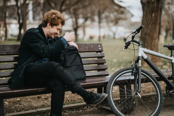 起業家は 自転車の横にある公園のベンチで平和な瞬間を楽しんでおり 仕事とライフスタイルのバランスを示しています — ストック写真