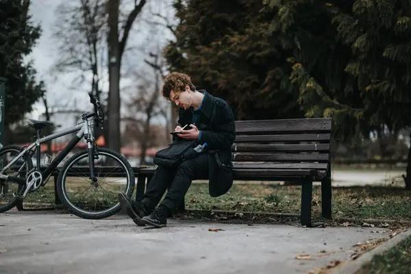 在宁静的公园里远程工作的男性商人 带着笔记本和自行车坐在长椅上 — 图库照片