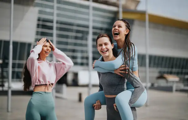 stock image Two young women in sports attire doing stretching exercises in a modern urban setting, showcasing fitness and healthy lifestyle.