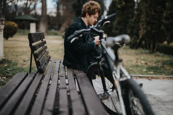 在安静的公园长椅上的自行车旁边 用智能手机远程工作的年轻的商业专业人士或企业家 — 图库照片