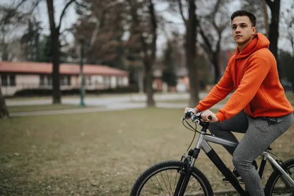 屋外で自転車に乗るカジュアルな服装のアクティブな若い大人 オーバーキャストされた日に公園の静けさに囲まれて — ストック写真