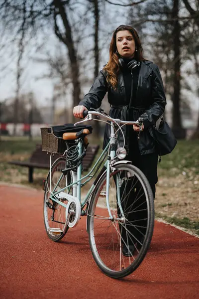 ヘッドフォンを持つ自信を持ったビジネスマンは 都市の環境に優しい通勤を体現する都市公園で自転車で歩きます — ストック写真