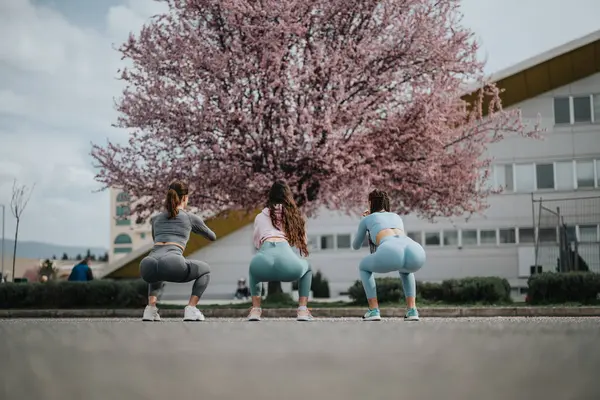 Fitness Orientierte Freunde Die Kniebeugen Mit Frühlingskirschblüten Machen Bringen Natürliche — Stockfoto
