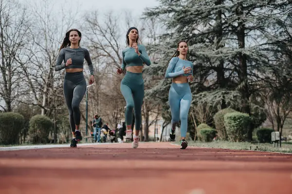 Three Young Female Athletes Running Track Park Showcasing Fitness Teamwork — Stock Photo, Image