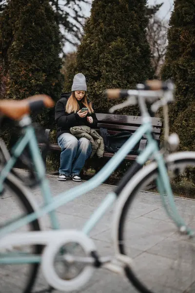 Junge Frau Nutzt Smartphone Auf Parkbank Neben Fahrrad — Stockfoto