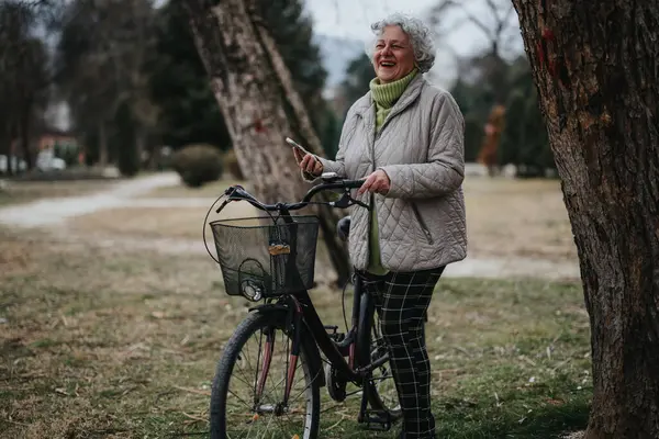 Femme Mûre Avec Vélo Debout Dans Parc Regardant Son Téléphone — Photo