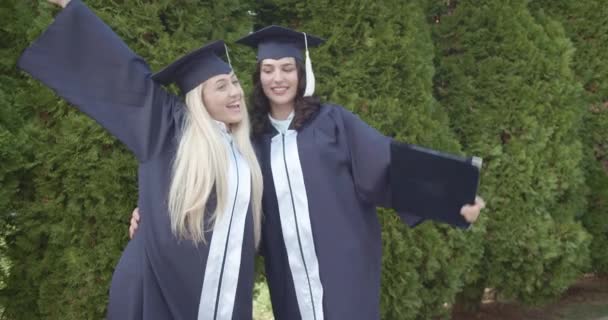 Dos Mujeres Graduadas Eufóricas Vestidas Con Gorras Vestidos Levantan Alegremente — Vídeos de Stock