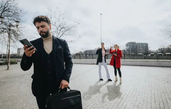 身着西装的职业男性 在城市背景下与同事们讨论如何使用智能手机 — 图库照片