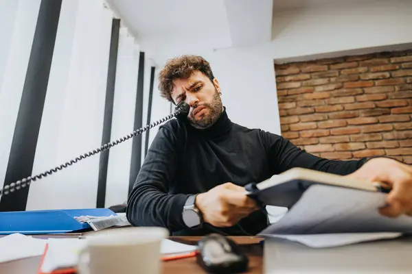 Hombre Frustrado Multitarea Con Teléfono Papeleo Escritorio Oficina Expresando Estrés —  Fotos de Stock