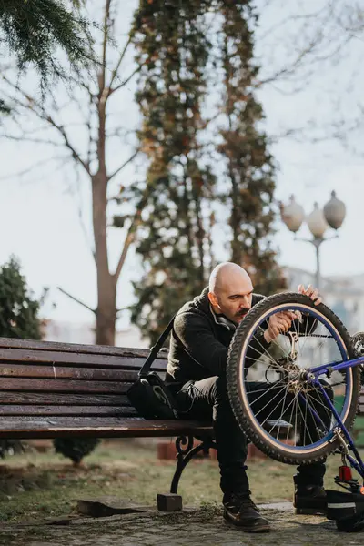 Focused Man Sitting Bench Repairing Wheel His Bicycle Serene Park — Stock Photo, Image