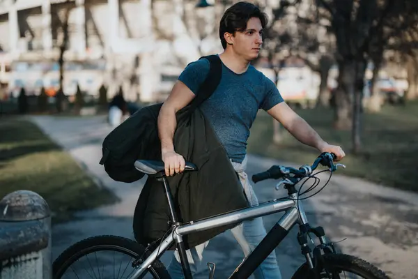 stock image A pensive man takes a break with his bike in a serene park, enjoying a moment of relaxation outdoors.