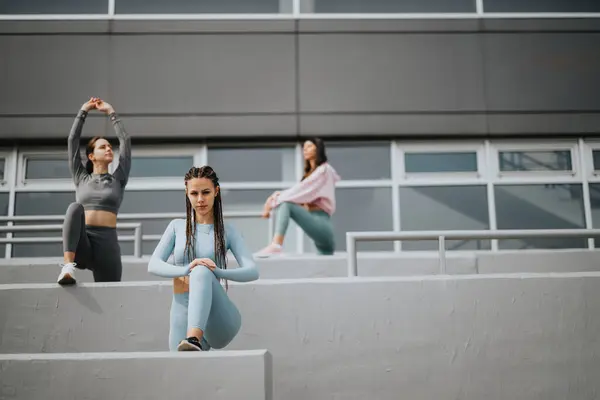 3名穿着运动服的年轻女性正在进行伸展运动 并准备就城市的具体步骤进行锻炼 — 图库照片