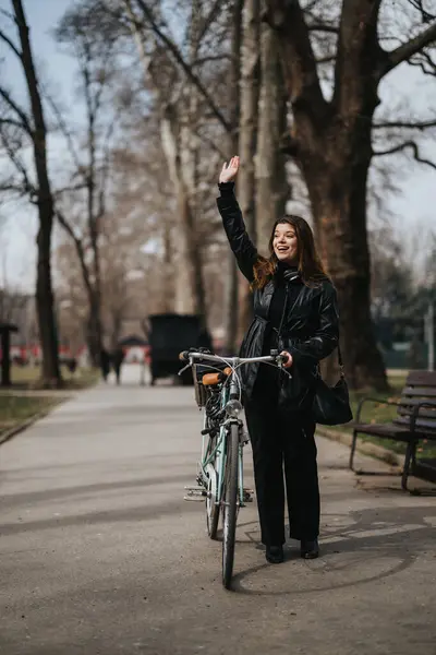 在城市公园里骑自行车的活跃的女商人向人打招呼 展示她在城市里进行的环保旅行 — 图库照片