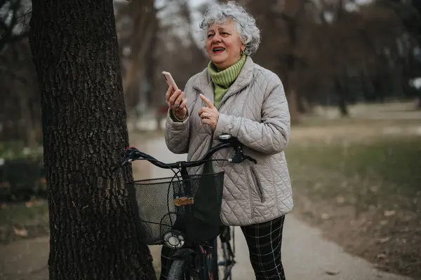 Sorridente Donna Matura Con Una Bicicletta Piedi Parco Sfogliando Suo — Foto Stock