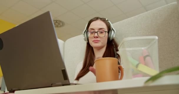在现代办公室里 当代员工一边一边一边一边一边一边用耳机听音乐 一边享受着喝咖啡的休息时间 — 图库视频影像