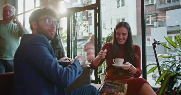 2人の友人は 居心地の良いカフェの設定でコーヒーを飲みながら楽しい瞬間を共有し 友情とカジュアルな社会的交流の暖かさを体現し 快適な雰囲気を作り出しています — ストック動画