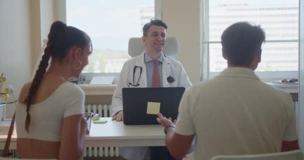 잘생긴 전문가 농담과 환자와 재미있는 대화를하고 사무실에서 긍정적인 분위기 — 비디오