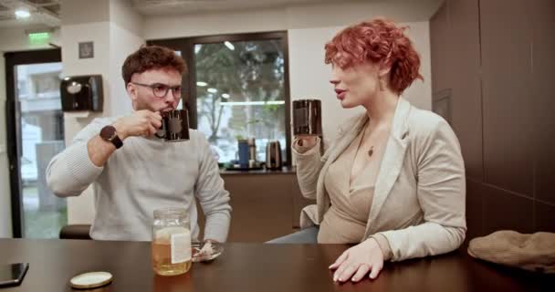 カジュアルなビジネスコーヒーブレイクの間に 2人の同僚は 明るいオフィススペースで飲み物について話し合ったり カマリーを育成したり 職場でのコラボレーションをしたりします — ストック動画