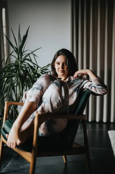 A relaxed young woman enjoys a quiet moment while sitting comfortably in a stylish chair, evoking a sense of contemplation and modern home ambiance.