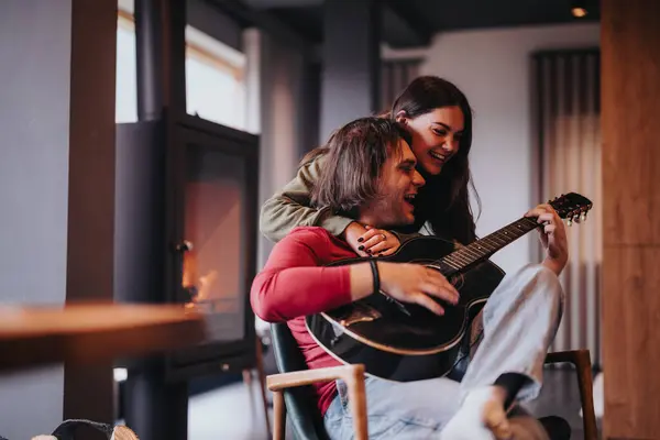自宅で居心地の良い暖炉でギターと一緒に時間を楽しむカップルの刺激的な瞬間 — ストック写真