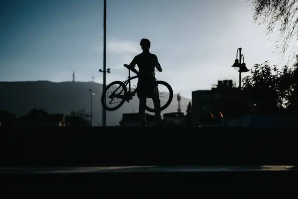 Spokojna Scena Człowieka Sylwetką Trzymającego Rower Parku Przy Wieczornym Świetle Zdjęcia Stockowe bez tantiem