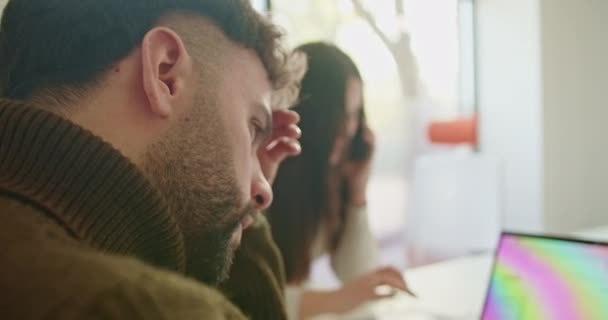 一个年轻的男人和一个女人在一个现代化的办公室里合作时都会感到压力 一个在打电话 另一个在笔记本电脑屏幕上审查数据 — 图库视频影像