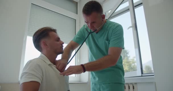 Specialista Středního Věku Používající Stetoskop Kontrolující Mladé Pacienty Dýchající Nemocničním — Stock video