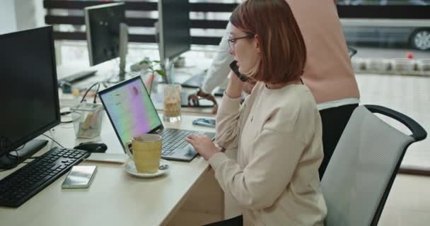 当同事们在办公室桌上合作时 这位年轻女士与一位客户在电话上协调一个新项目 讨论细节和费用 — 图库视频影像