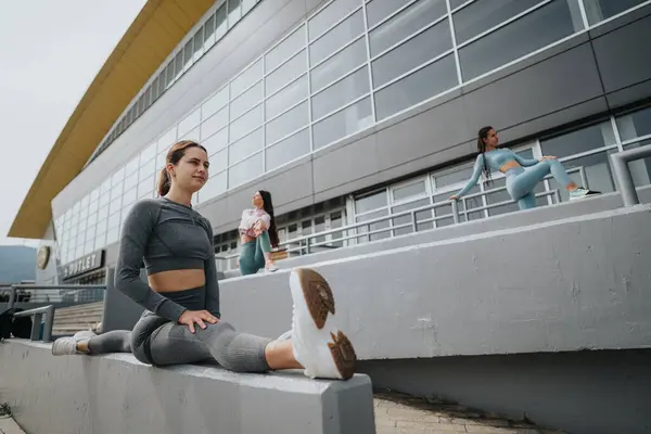 三个穿着运动服的女人在现代建筑外锻炼 伸展和放松休息一下 — 图库照片