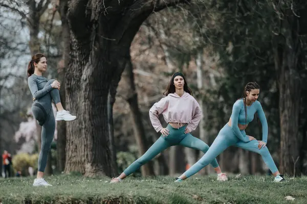 Three Determined Female Athletes Perform Stretching Exercises Serene Park Setting — Stock Photo, Image