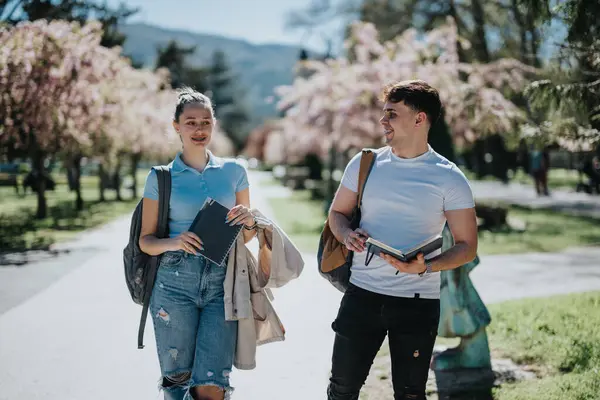 Dois Jovens Adultos Com Livros Mochilas Conversando Sorrindo Parque Iluminado — Fotografia de Stock