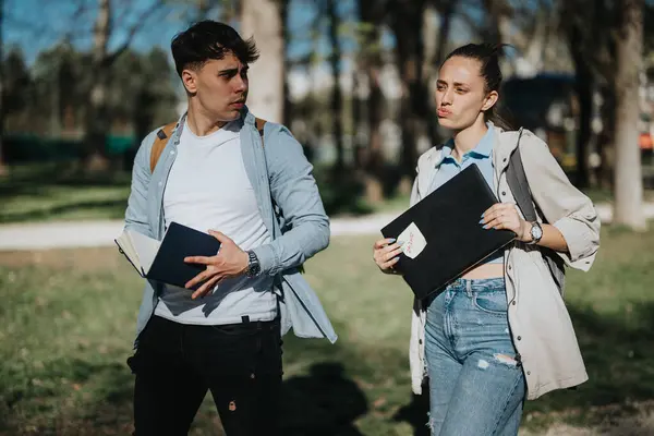 在阳光灿烂的日子里 两个拿着笔记本的大学生在城市公园进行了严肃的讨论 分析了考试后的话题 — 图库照片