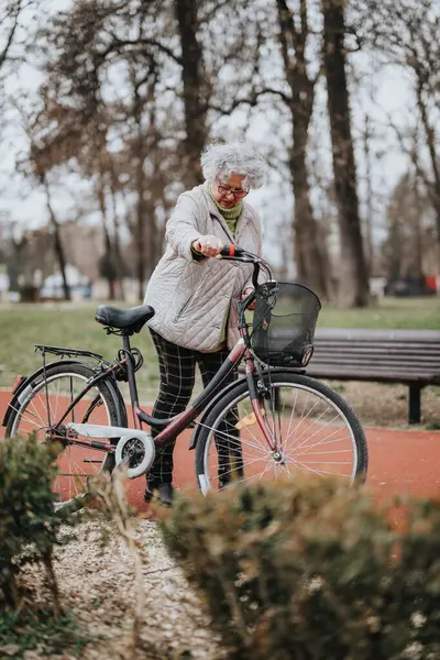 Energetic elderly woman with her bicycle outdoors, showcasing an active retirement life.