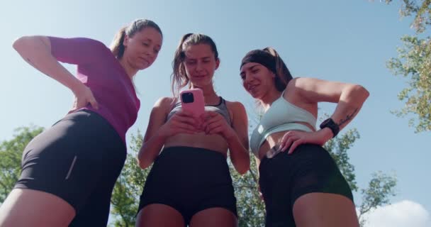 三个运动朋友从运动中休息 在公园里和智能手机分享片刻 — 图库视频影像