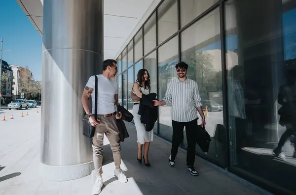 stock image Three professionals engaged in a discussion while walking outside a contemporary urban building, symbolizing teamwork and strategy.