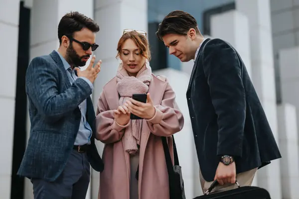 Three young professionals discuss project costs and strategies on a smart phone for enhanced business growth and profitability in a city environment.