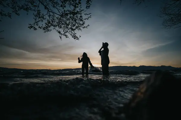 Dos Chicas Como Siluetas Divirtiéndose Junto Lago Salpicando Agua Disfrutando Fotos De Stock